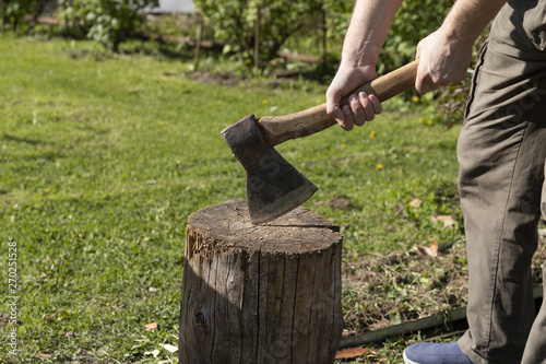 Men's hands holding an axe on a stump