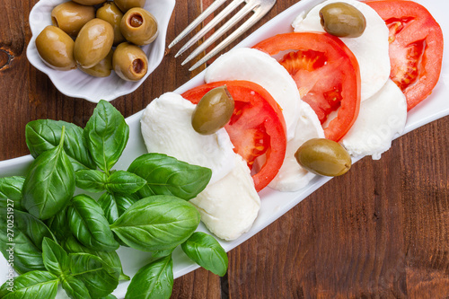 Swieza mozzarella z plastrarmi pomidora i listkami bazyli. Rustykalna kuchnia. Wegetarianskie danie. Vege salatka. photo