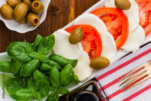 Swieza mozzarella z plastrarmi pomidora i listkami bazyli. Rustykalna kuchnia. Wegetarianskie danie. Vege salatka. photo