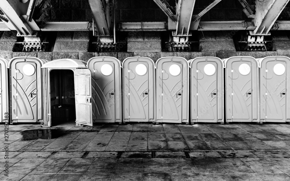 Row of portable, plastic toilets, placed under old bridge. All but one closed Row of portable, plastic toilets, placed under old bridge. All but one closed