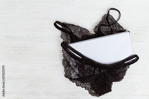 Set of black lingerie in white box. Mock up. Fashionable female underwear on wooden background. Beautiful gift. Beauty, fashion, blogger concept.