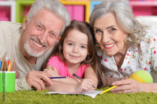 Portrait of grandparents playing with their grandaughter while lying on floor