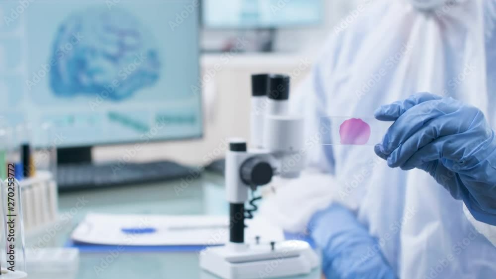 Rack focus on researcher in laboratory using a sample under the microscope. Professional and high end research center Rack focus on researcher in laboratory using a sample under the microscope. Professional and high end research center