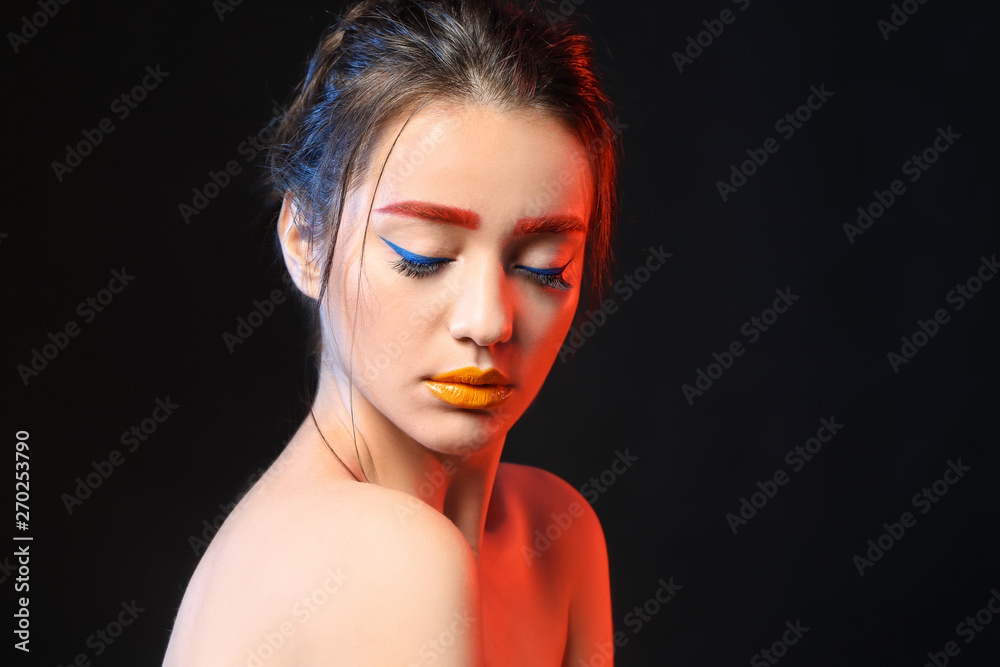 Young woman with dyed eyebrows and creative makeup on black background Young woman with dyed eyebrows and creative makeup on black background