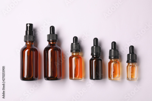 Bottles of essential oils on light background, top view. Cosmetic products