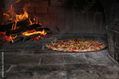 Burning firewood and tasty pizza in oven at restaurant kitchen