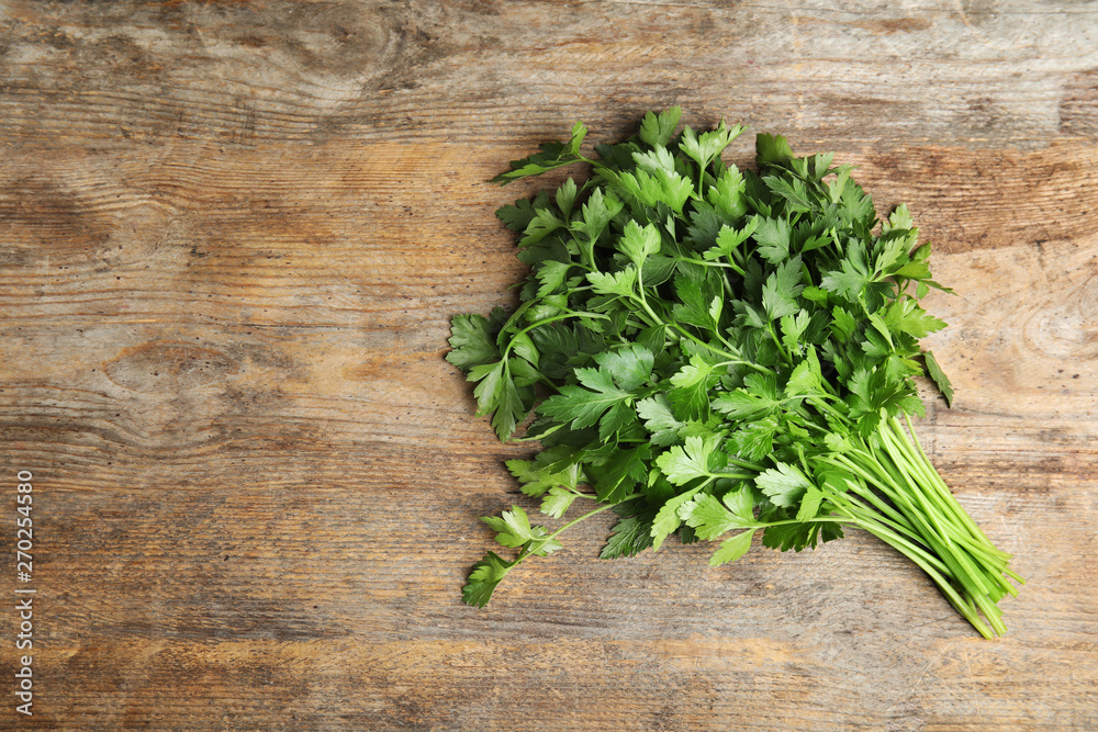 Bunch of fresh green parsley on wooden background, view from above. Space for text Bunch of fresh green parsley on wooden background, view from above. Space for text