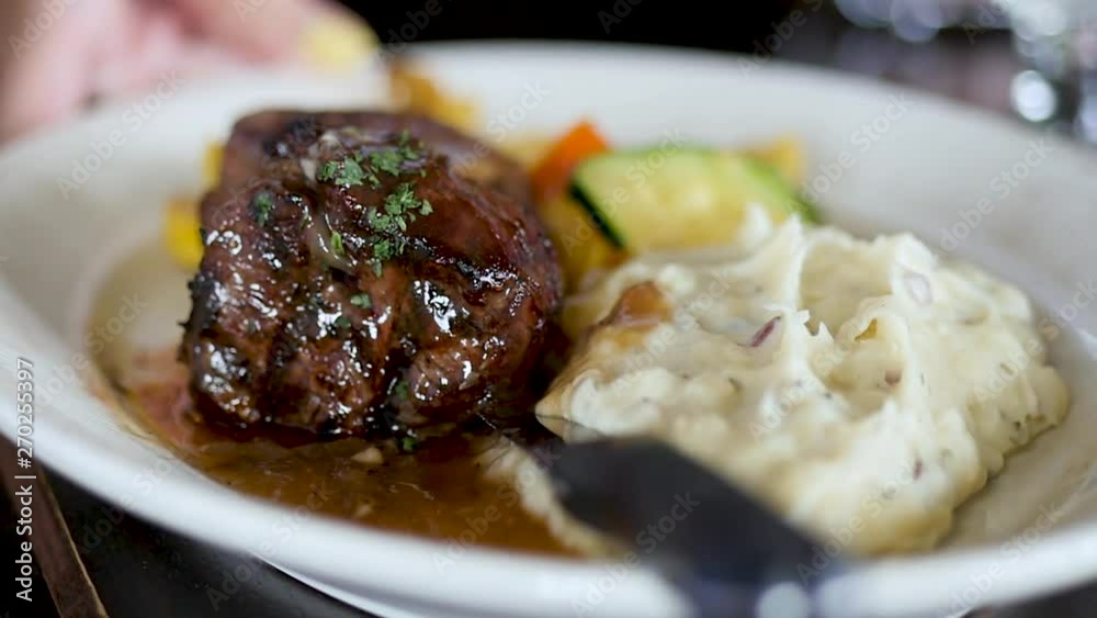 close up of steak and potato plate put on table. This is a close up shot of a waiter placing a plated sirloin steak and mashed potatoes on a dark wood restaurant table in slow motion. close up of steak and potato plate put on table. This is a close up shot of a waiter placing a plated sirloin steak and mashed potatoes on a dark wood restaurant table in slow motion.