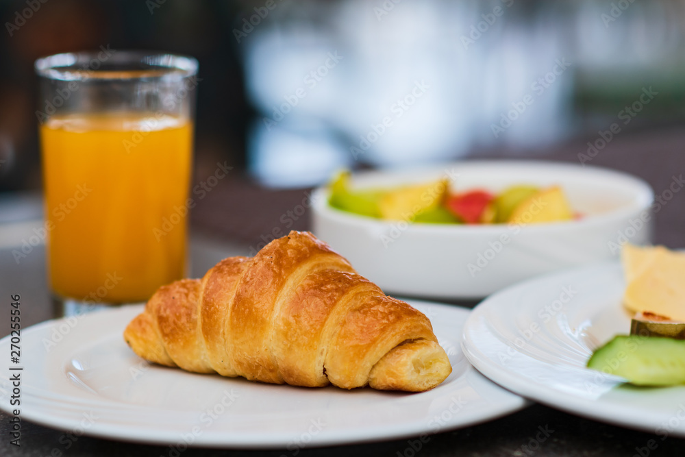 Continental breakfast with fresh croissant, orange juice and fruits, selective focus Continental breakfast with fresh croissant, orange juice and fruits, selective focus