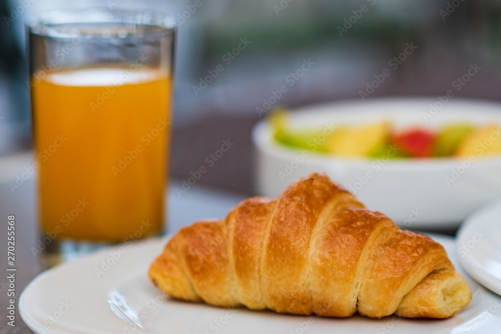 Continental breakfast with fresh croissant, orange juice and fruits, selective focus Continental breakfast with fresh croissant, orange juice and fruits, selective focus