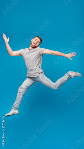 Funny millennial guy jumping in air and fooling