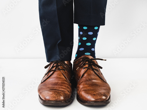 Office manager standing in stylish shoes  blue pants and bright  colorful socks on a white  isolated background. Close-up. Studio photo. Concept of lifestyle  fun and elegance