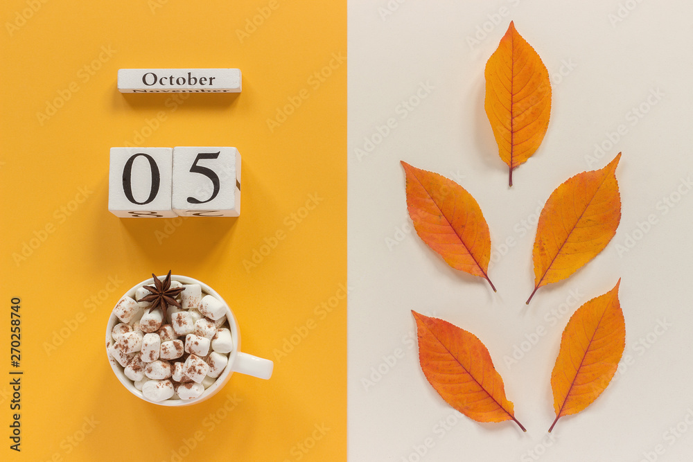 Autumn composition. Wooden calendar October 5, cup of cocoa with marshmallows and yellow autumn leaves on yellow beige background. Top view Flat lay Mockup Concept Hello September