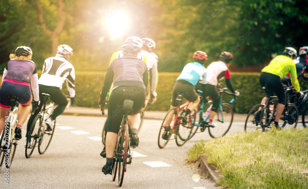 Fototapeta premium Radrennen mit Ragrennfahren in einer Kurve im Gegenlicht am Abend