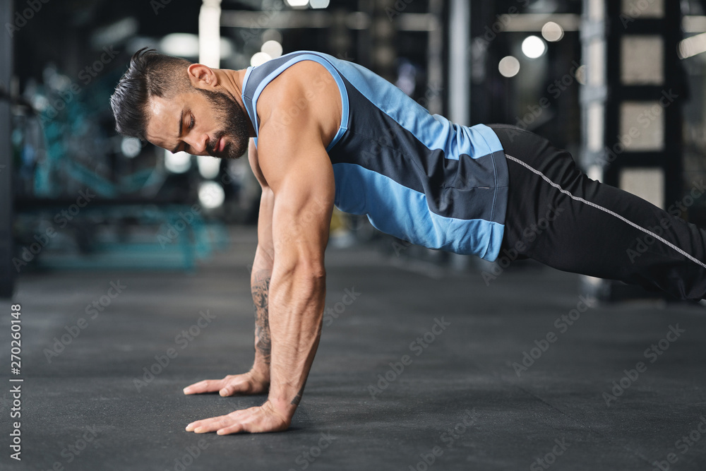 Fototapeta premium Sporty young man doing pushups in gym