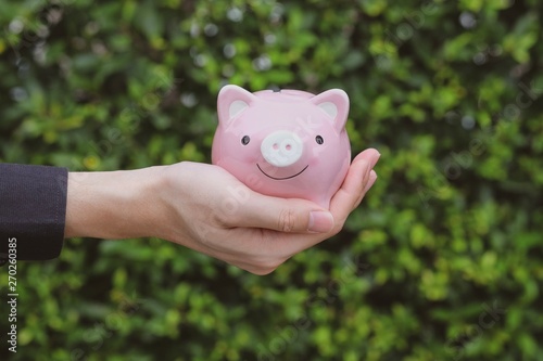 Hand holding pink piggy bank. Savings and invest for future.