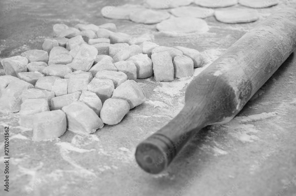 Concept of cooking dumplings: dough, flour and rolling pin on the kitchen table.