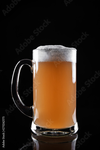 Mug of foamy beer isolated on dark background