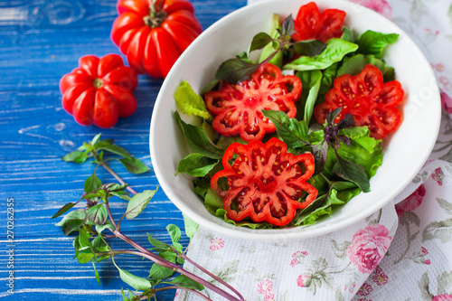 italian salad with tomato in white dish on blue table photo