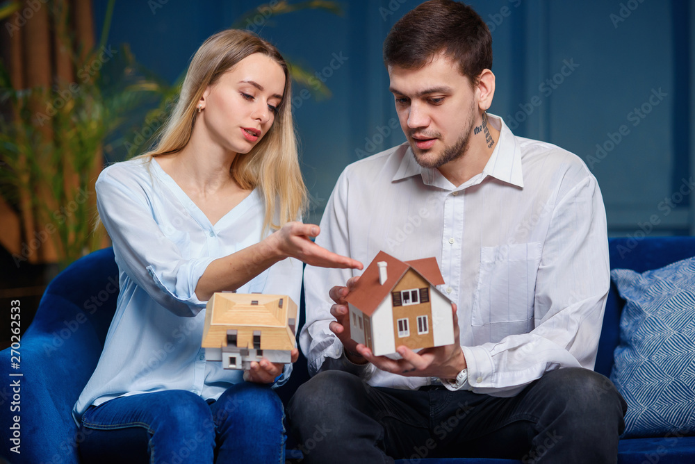 Cute caucasian man and woman discussing two model of 3d maket of house. Cute caucasian man and woman discussing two model of 3d maket of house.