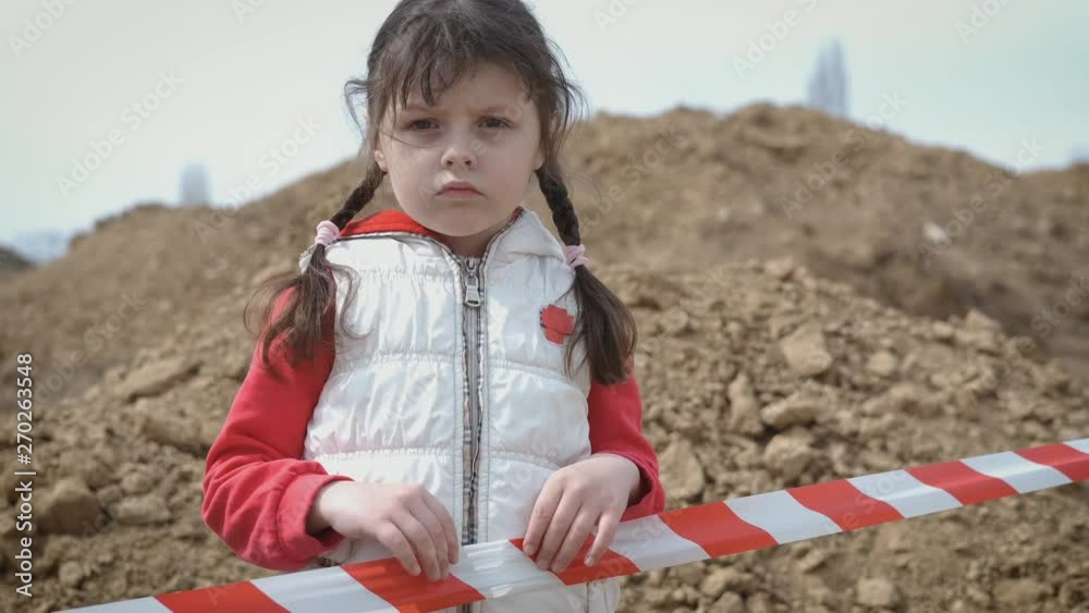 Depressed child. Sad little girl behind the fencing tape. War child. Depressed child. Sad little girl behind the fencing tape. War child.