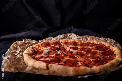 pizza peperoni on black stone background