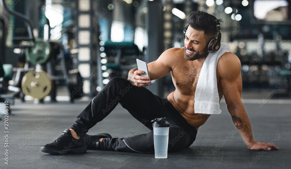 Muscular man using cellphone at gym, free space Muscular man using cellphone at gym, free space
