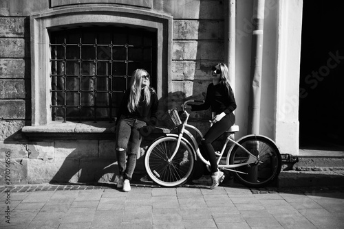 Happy friends having fun walking in city center. Beautiful young positive girls spend summer holidays. Two smiling pretty teenagers travel around old wonderful European city. Joint vacation concept