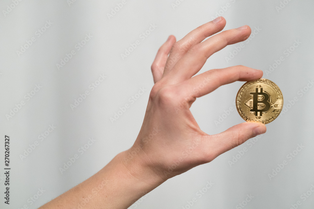 Cryptocurrency golden bitcoin coin. Man holding in hand symbol of crypto currency - electronic virtual money for web banking and international network payment, selective focus, toned Cryptocurrency golden bitcoin coin. Man holding in hand symbol of crypto currency - electronic virtual money for web banking and international network payment, selective focus, toned