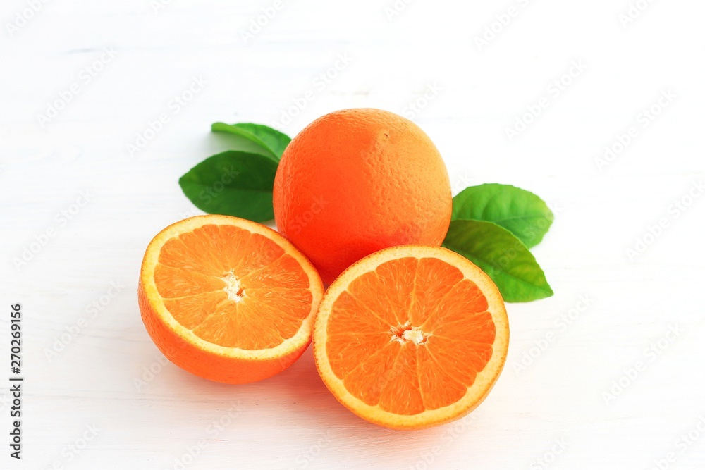 Orange fruit and one cut in half, with leaf isolated on white background. Orange fruit and one cut in half, with leaf isolated on white background.