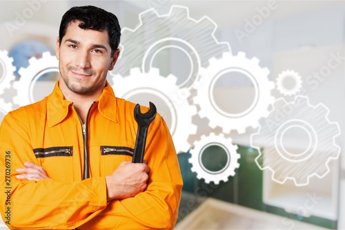 Cheerful worker holding wrench on kitchen background, man plumber.