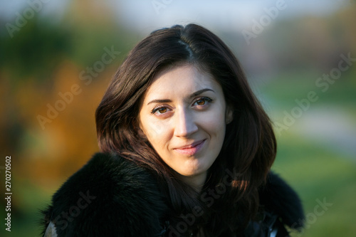 Autumn close up outdoors portrait of beautiful woman. Сlothes with fur collar and forest view on the background. © jonnyslav