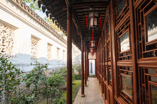 Column passage with china culture bulding, lamps and small garden and white wall on background, tiled floor