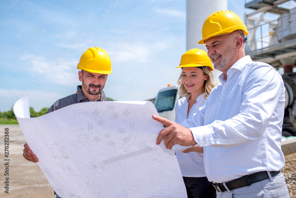 Group of engineers on site, wear safety helmets, discussing construction plan and exchanging ideas Group of engineers on site, wear safety helmets, discussing construction plan and exchanging ideas