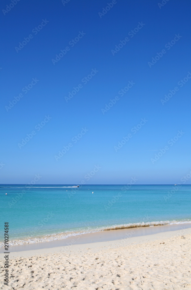 Sandy tropical beach with waverunner in the distance, travel background Sandy tropical beach with waverunner in the distance, travel background