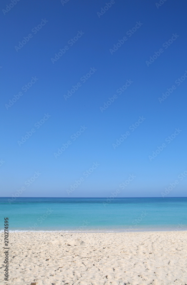 Sandy tropical beach with turquoise sea and clear blue sky travel background