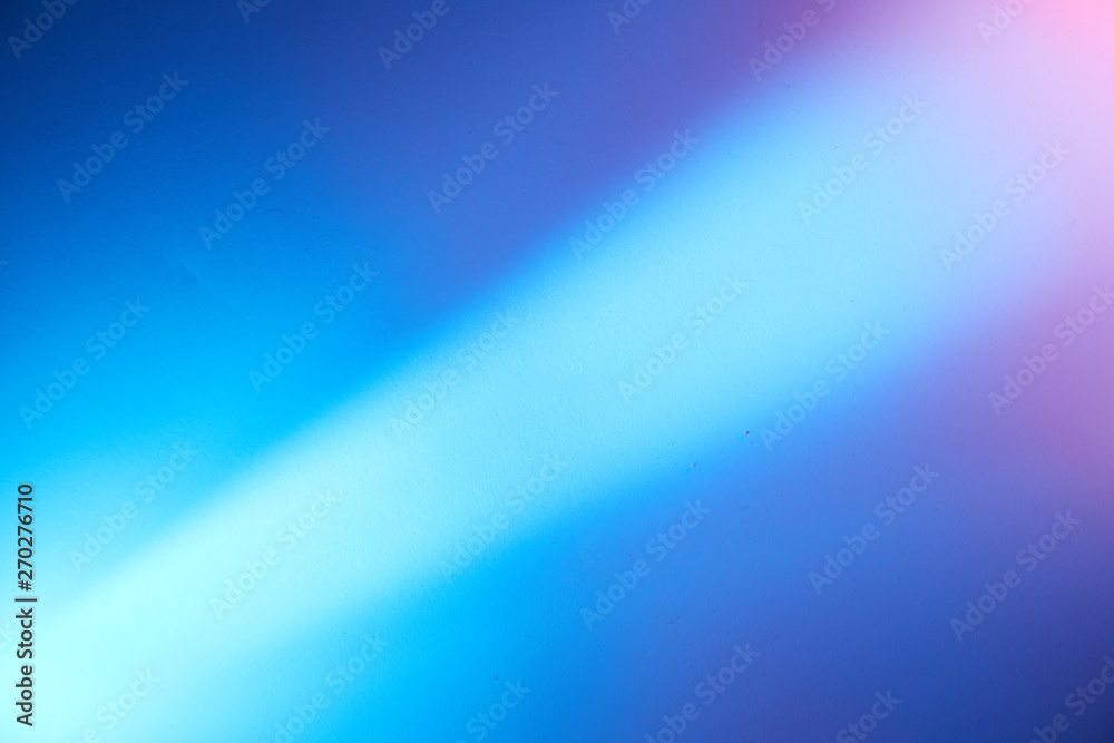 On a blurred light blue background, a diagonal light beam of light with a transition to a pink spot