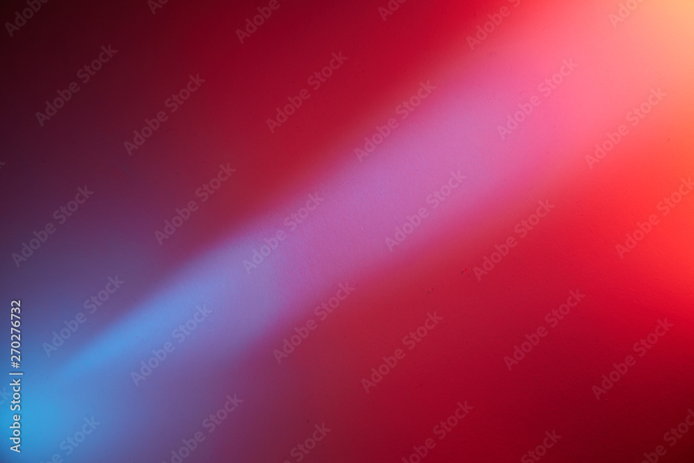 On a red blurred background, a blue diagonal beam of light with a transition to a light red spot of light