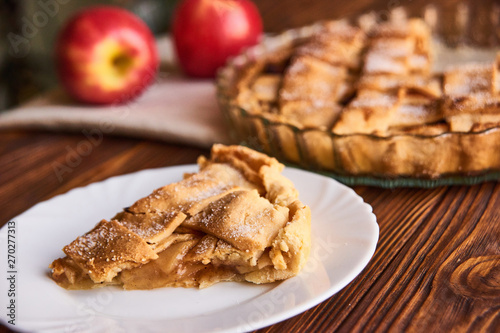 Eating sweet food context. Traditional holidays apple pie, slice on white plate and apples. Relishing sweet treats