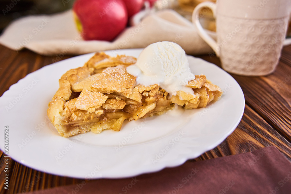 Tasty homemade apple pie, slice with ice cream. Apples. Plate, linen towel Wooden background Cup of tea Tasty homemade apple pie, slice with ice cream. Apples. Plate, linen towel Wooden background Cup of tea