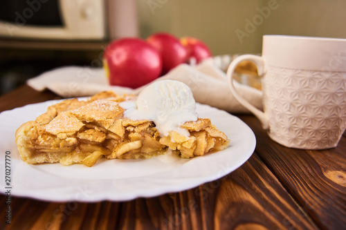 Tasty homemade apple pie, slice with ice cream. Apples. Plate, linen towel Wooden background Cup of tea