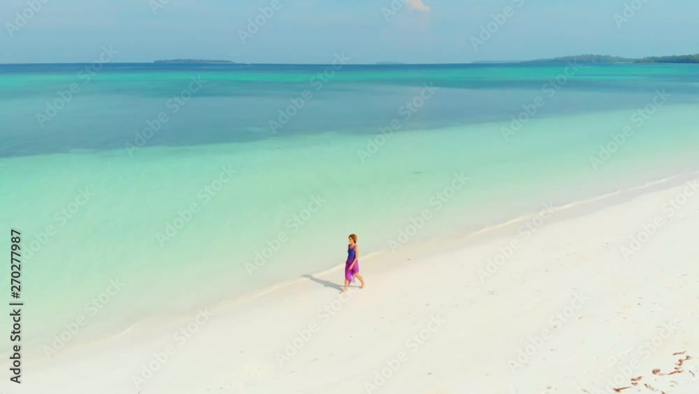 Aerial slow motion: Woman walking on white sand beach turquoise water tropical coastline Pasir Panjang Kei Islands Indonesia Moluccas Maluku Indonesia scenic travel destination Aerial slow motion: Woman walking on white sand beach turquoise water tropical coastline Pasir Panjang Kei Islands Indonesia Moluccas Maluku Indonesia scenic travel destination