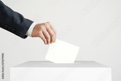 Man putting a ballot into a voting box.