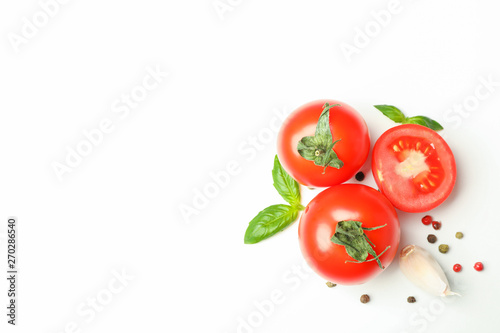 Fresh cherry tomatoes with basil, pepper and garlic on white background, space for text and top view. Ripe vegetables