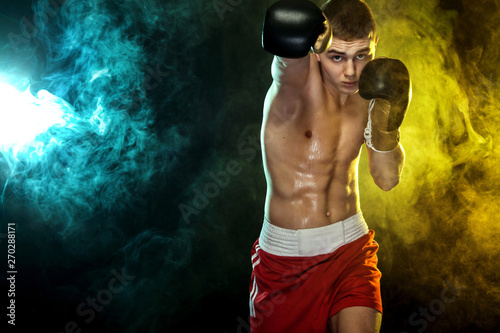 Sportsman, man boxer fighting in gloves. on black background with color smoke. Copy Space. © Mike Orlov