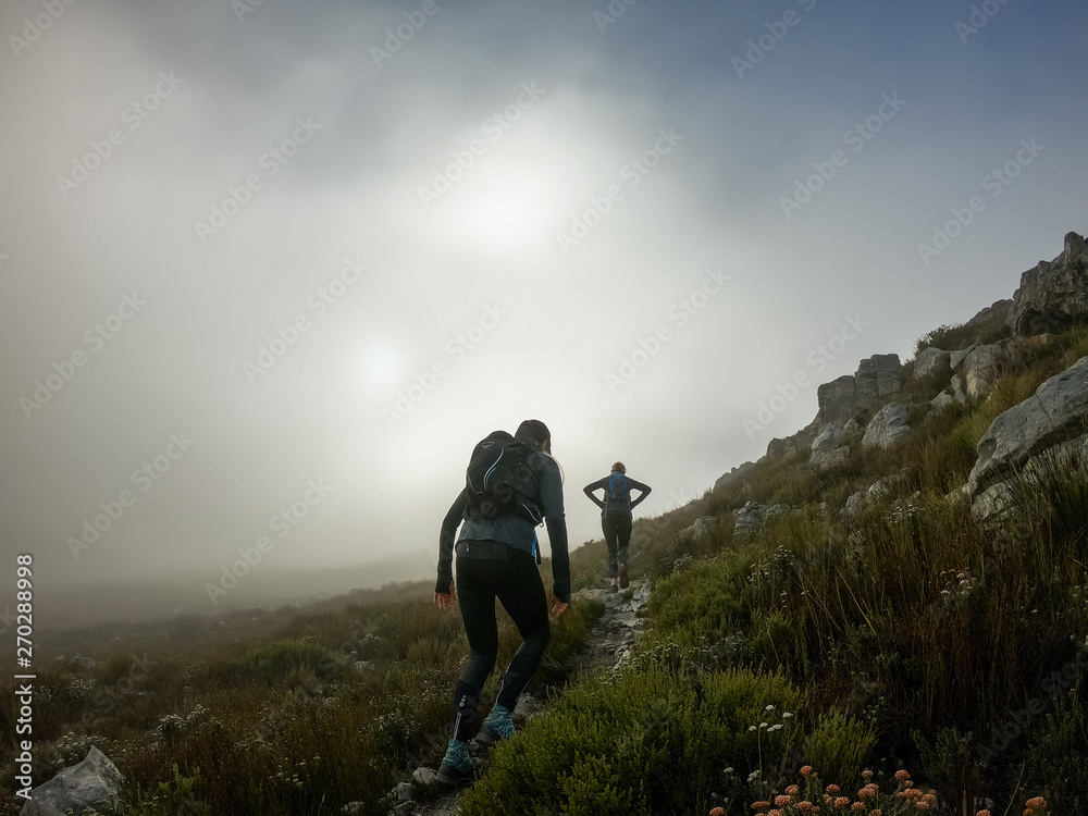 Two trail runners high up on on a mountain with mist