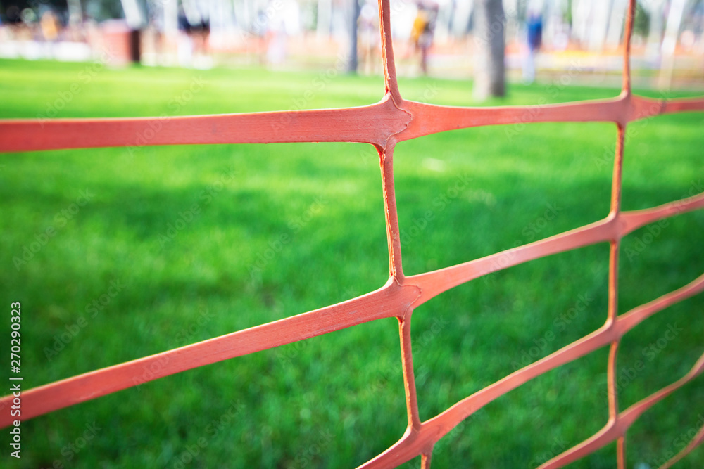 Orange plastic mesh. Drawn around the grass. Orange plastic mesh. Drawn around the grass.