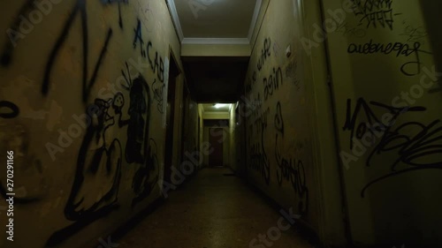 Old Apartment,Ghetto Building,long Dark Hallway.Tracking inside a dark long hallway of a ghetto apartment complex.Graffiti vandalism and abandonment in a poverty stricken neighbourhood.