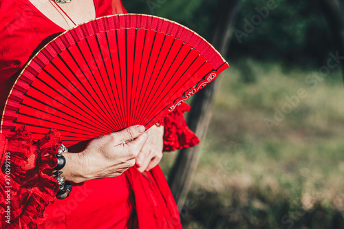 Woman in red dress with hand red open fan and bracelet