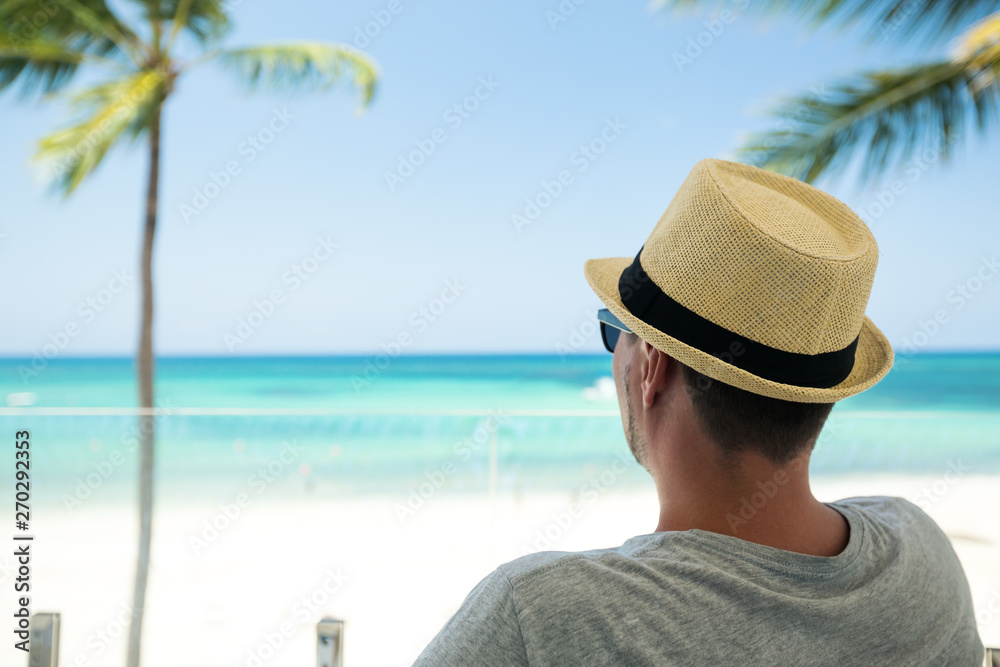 Man in summer hat enjoy watching the sea view at balcony